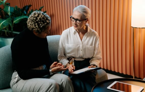 Two professional women engaged in a business discussion indoors with documents.